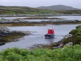 Small fishing boat moored in a sheltered inlet surrounded by seaweed on the Hebrides, Scotland