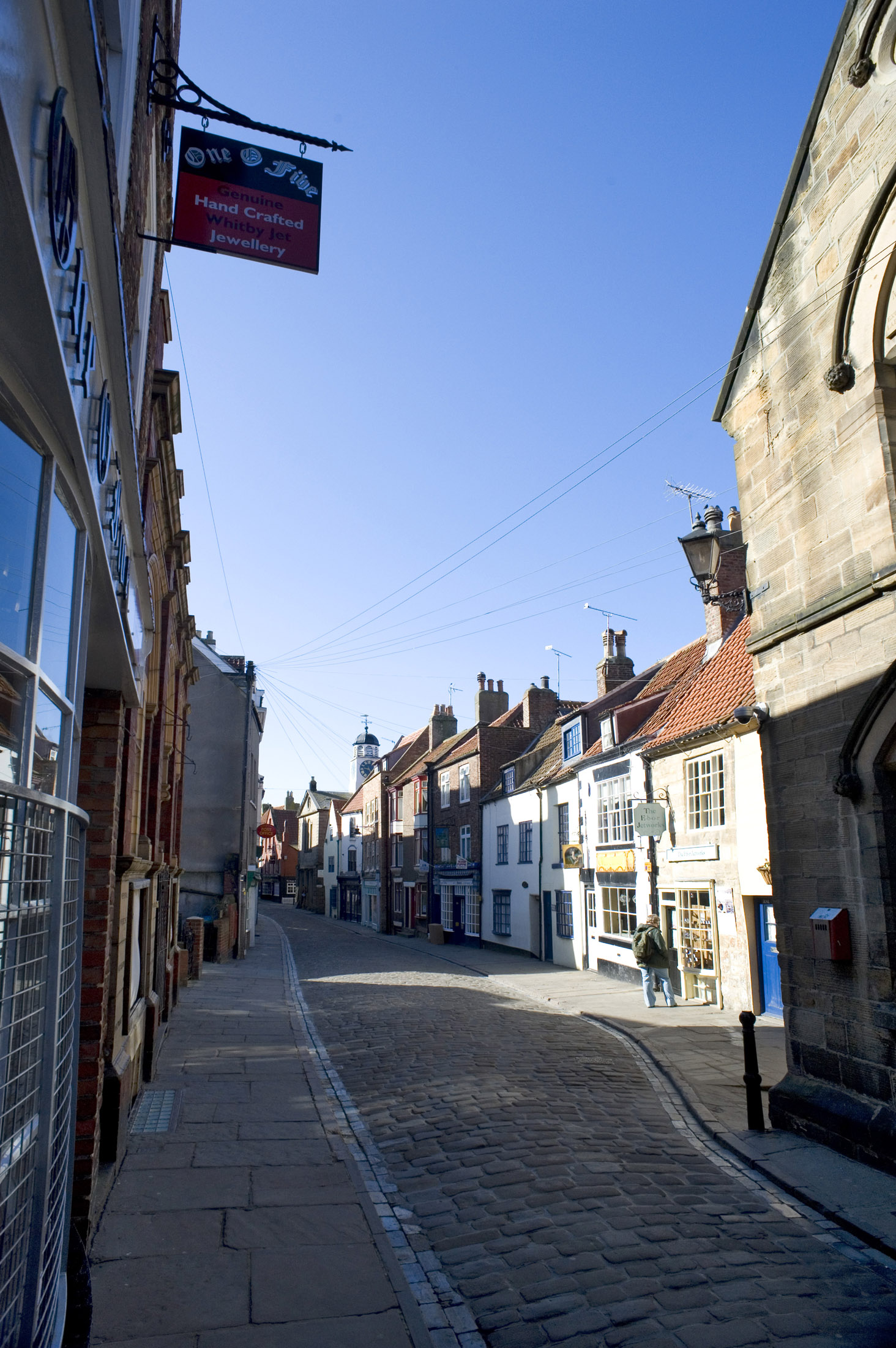 an image of early morning sun shines on the quaint shops of church street, whitby