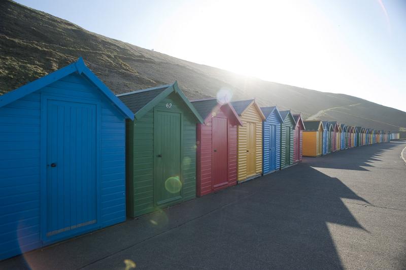 a line of beach huts on the shore at whitbys west cliff