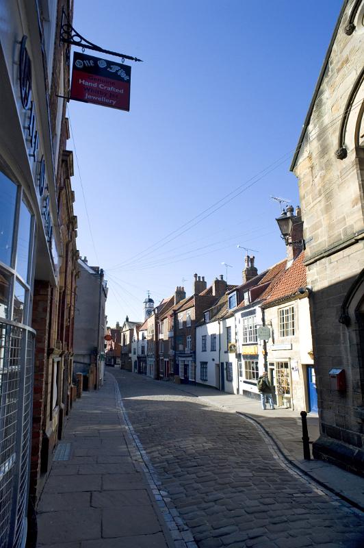 church street in the sun early morning sun shines on the quaint shops of church street, whitby