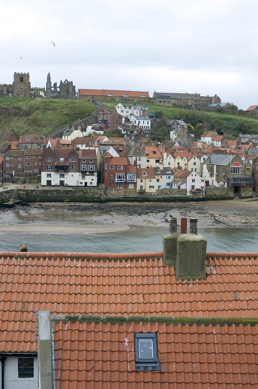 tiled roof tops looking over tiled cottage roof tops to the lower harbour and rows of cottages with the abbey and church on the hill