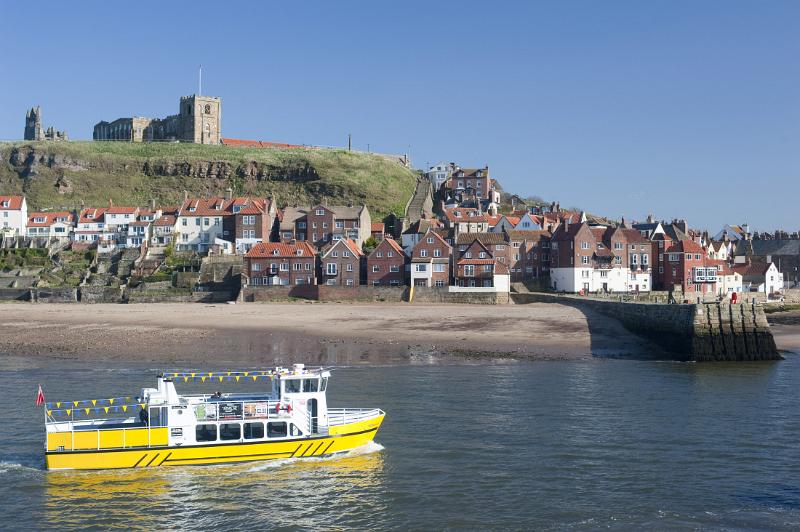 whitby pleasure cruise bright yellow trourist cruise boat on whitby lower harbour with the abbey behind