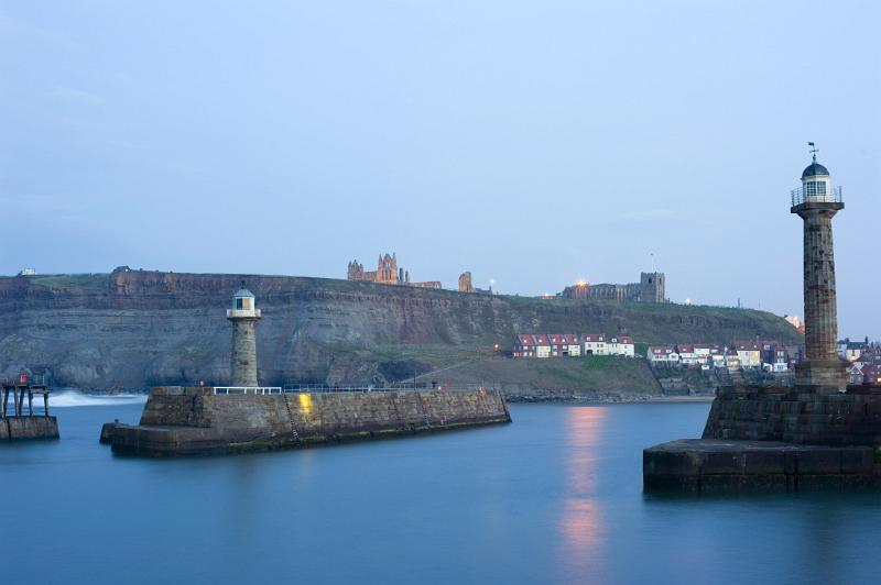 whitby harbour dusk a still dusk over whitby lower harbour, with the piers, lighhouses, fishermans cottages and the abbey on the hill in view