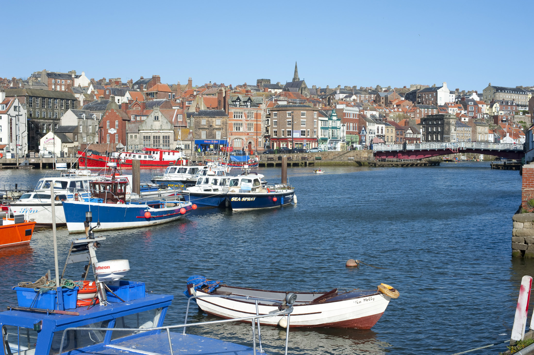 an image of boats moored in the upper harbour of whitby, the swing bridge can be seen at the right leading to the lower harbour
