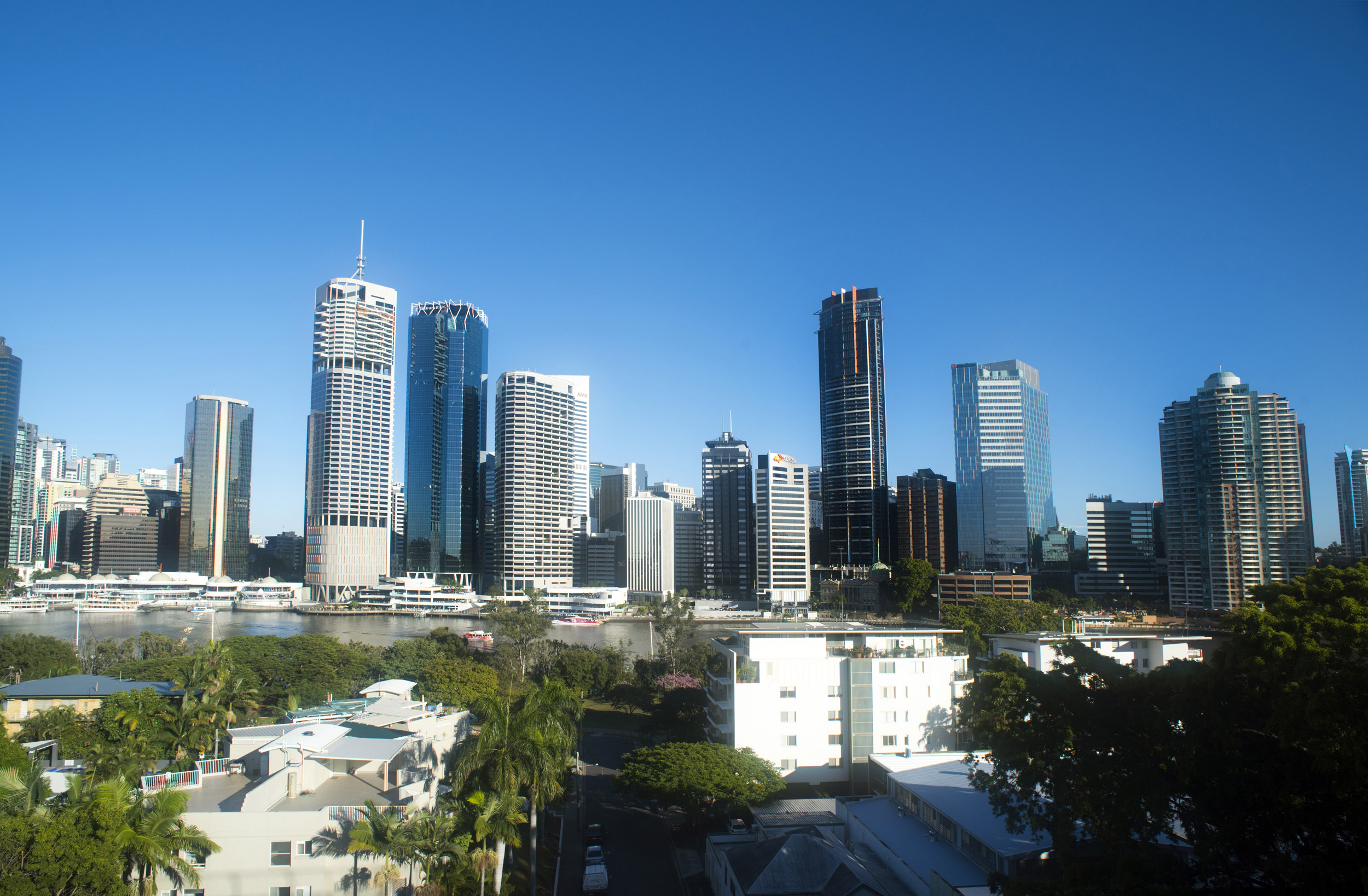 an image of A beautiful, panoramic view of Brisbane city skyline with skyscrapers, buildings and river on a clear, blue sunny day.