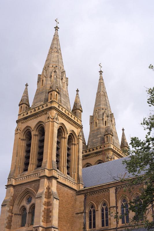 Ornate stone spires of Adelaide Cathedral, Australia against a cloudy grey sky viewed from below