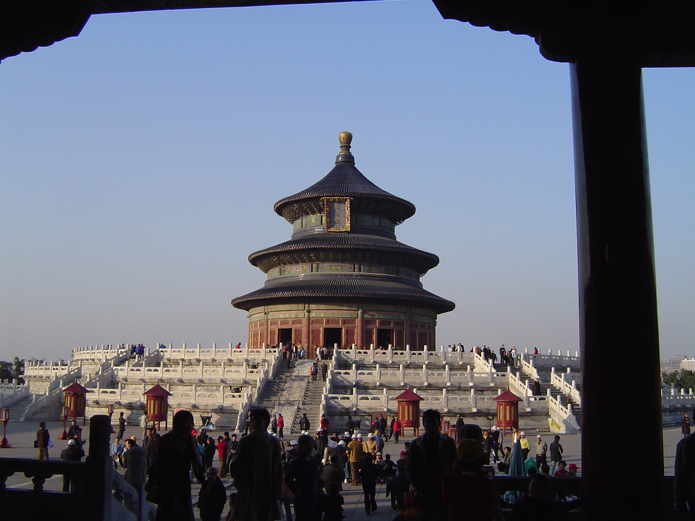 an image of Random Tourists at Famous Temple of Heaven in China, the Hall of Prayer for Good Harvests, on Lighter Blue Sky Background.