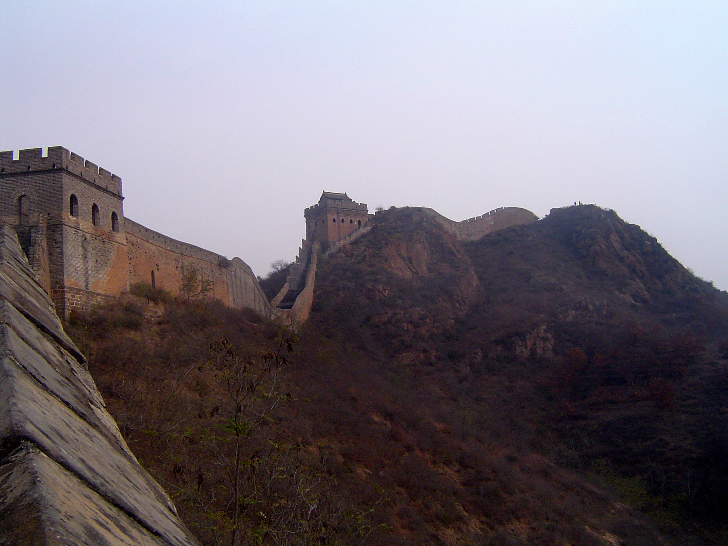 an image of Famous Stone Made Great Wall of China on Hills. One of the Wonders of the World. Captured on Very Light Blue Sky Background.