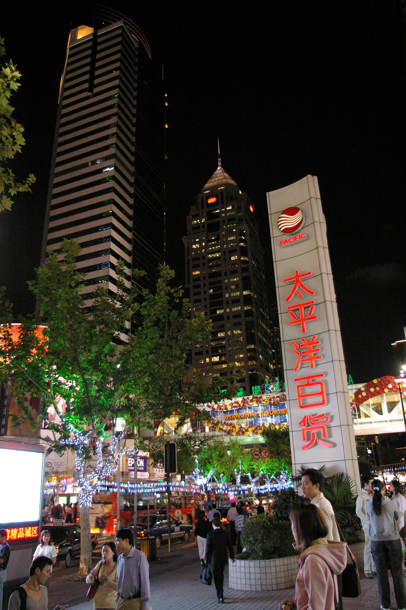 an image of High Rise Architectural Buildings in Chinese City View with Random Busy People. Captured at Night Time.