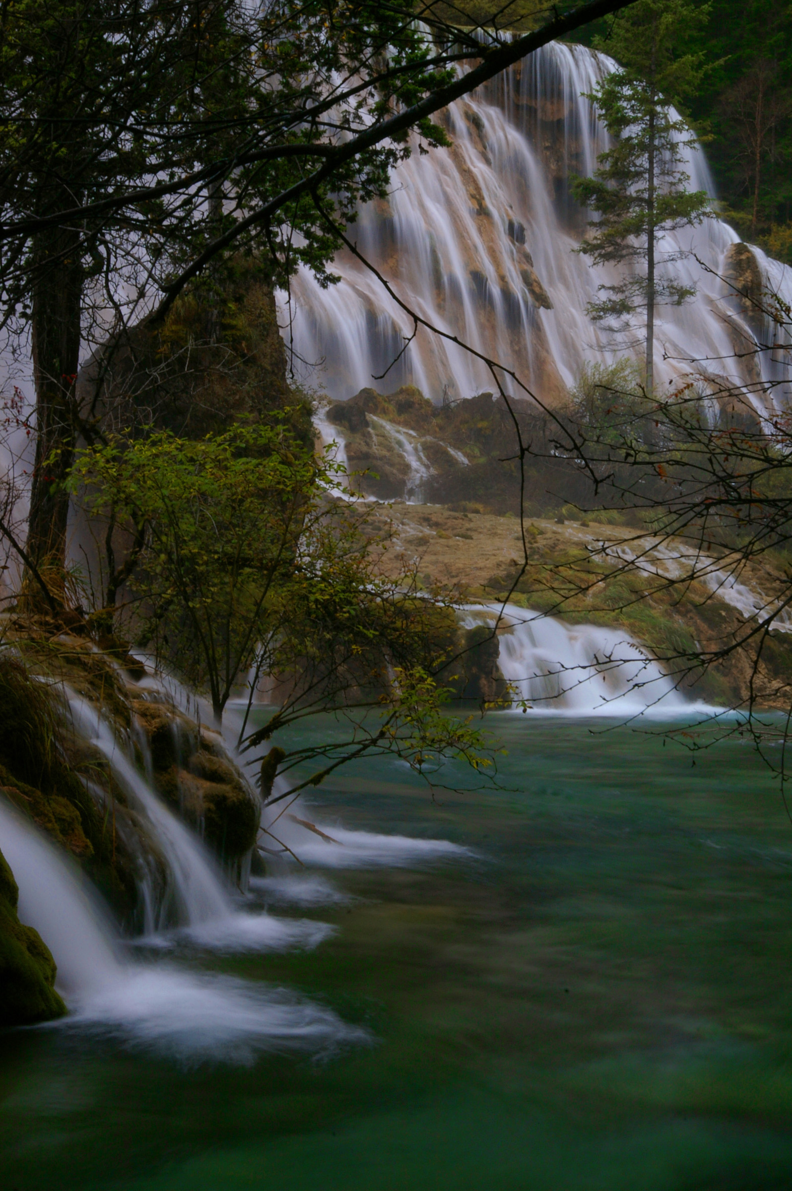 an image of Waterfalls cascading down a mountainside over mossy green rocks in a tranquil scene of great natural beauty