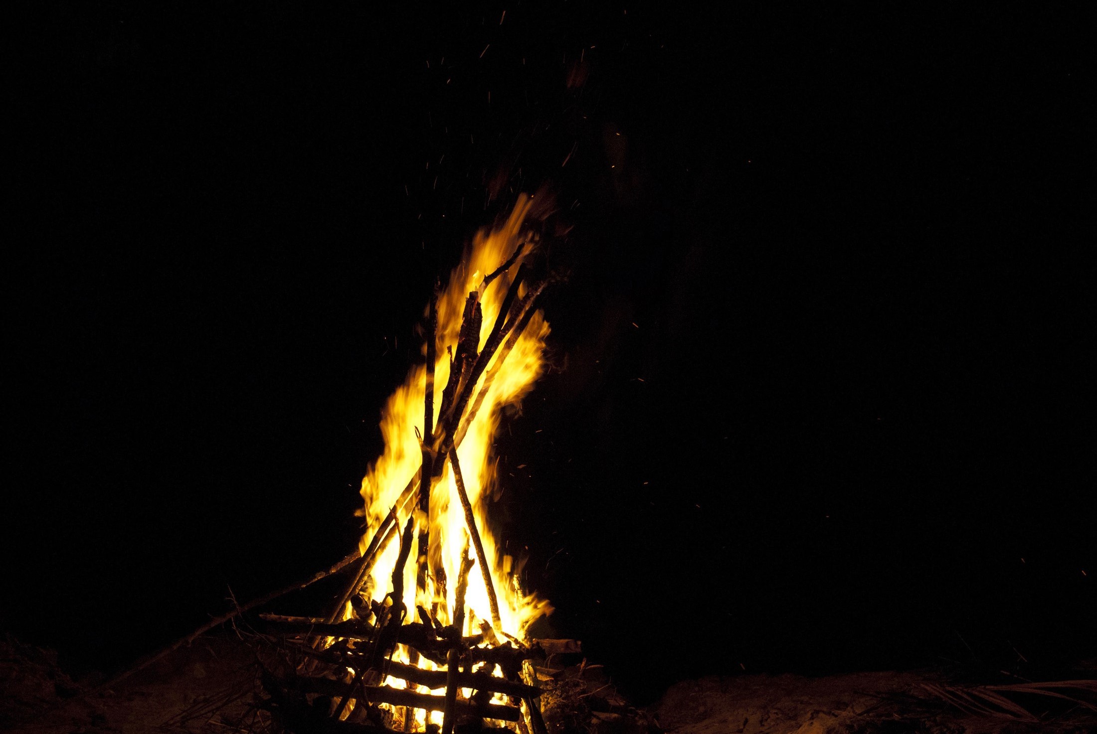 an image of Blazing camp fire with fiery orange flames shooting into the night sky with copyspace