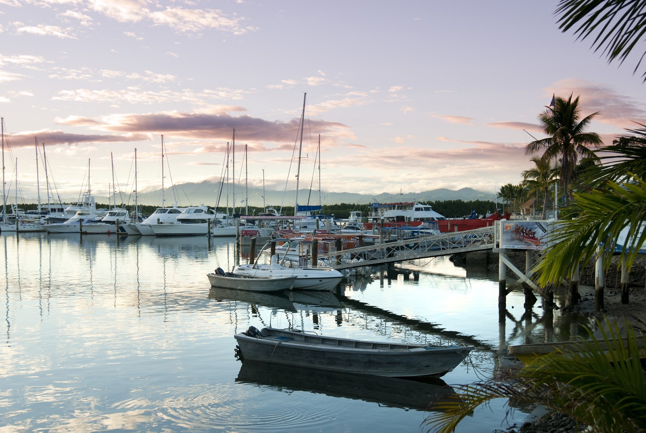 an image of Beautiful delicate pink sunset over Denarau Marina, Fiji, with pleasure boats and yachts moored in the sheltered water