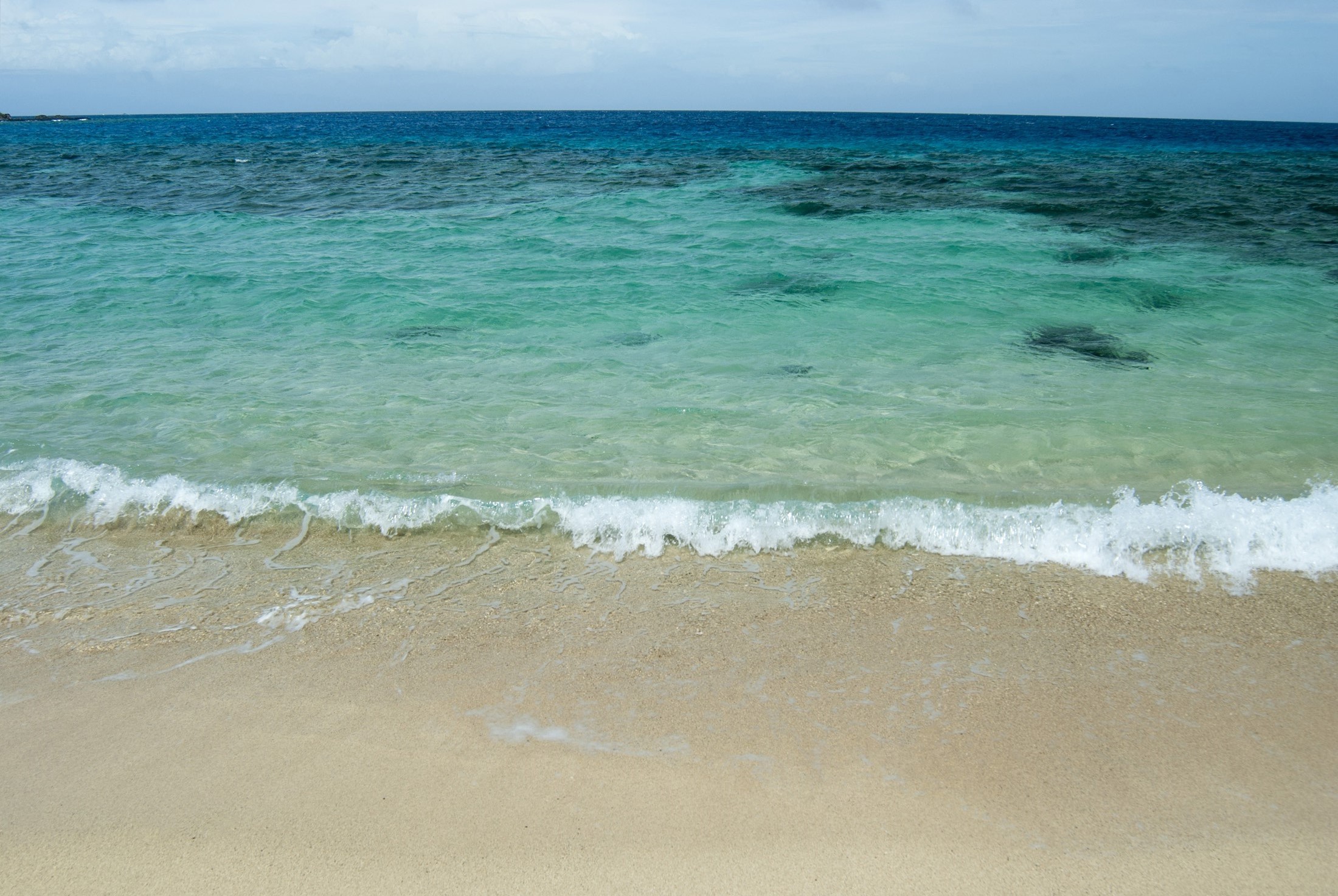 an image of Environmental background of an idyllic sandy beach and clear blue tropical ocean suitable for travel and vacation