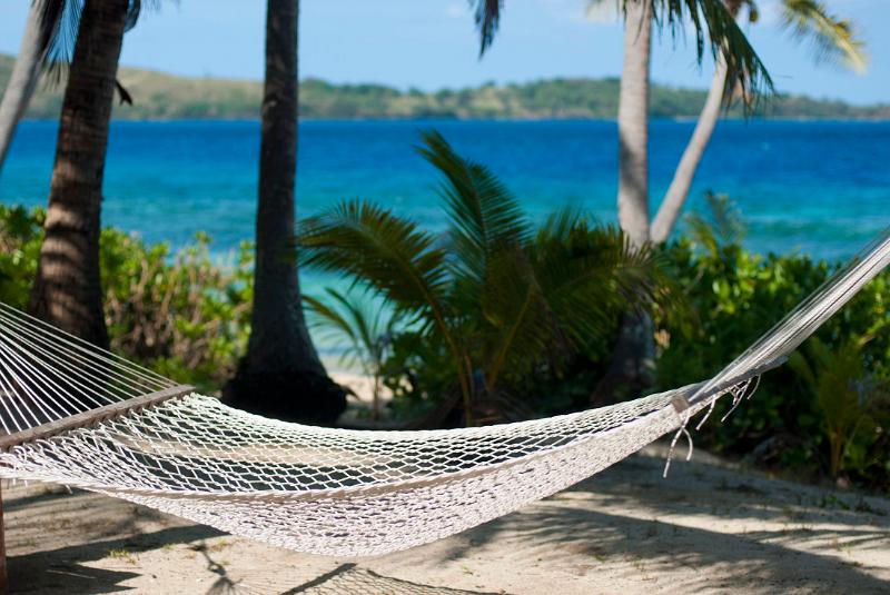 Beautiful scenic background of an empty hammock at a tropical beach overlooking the blue ocean