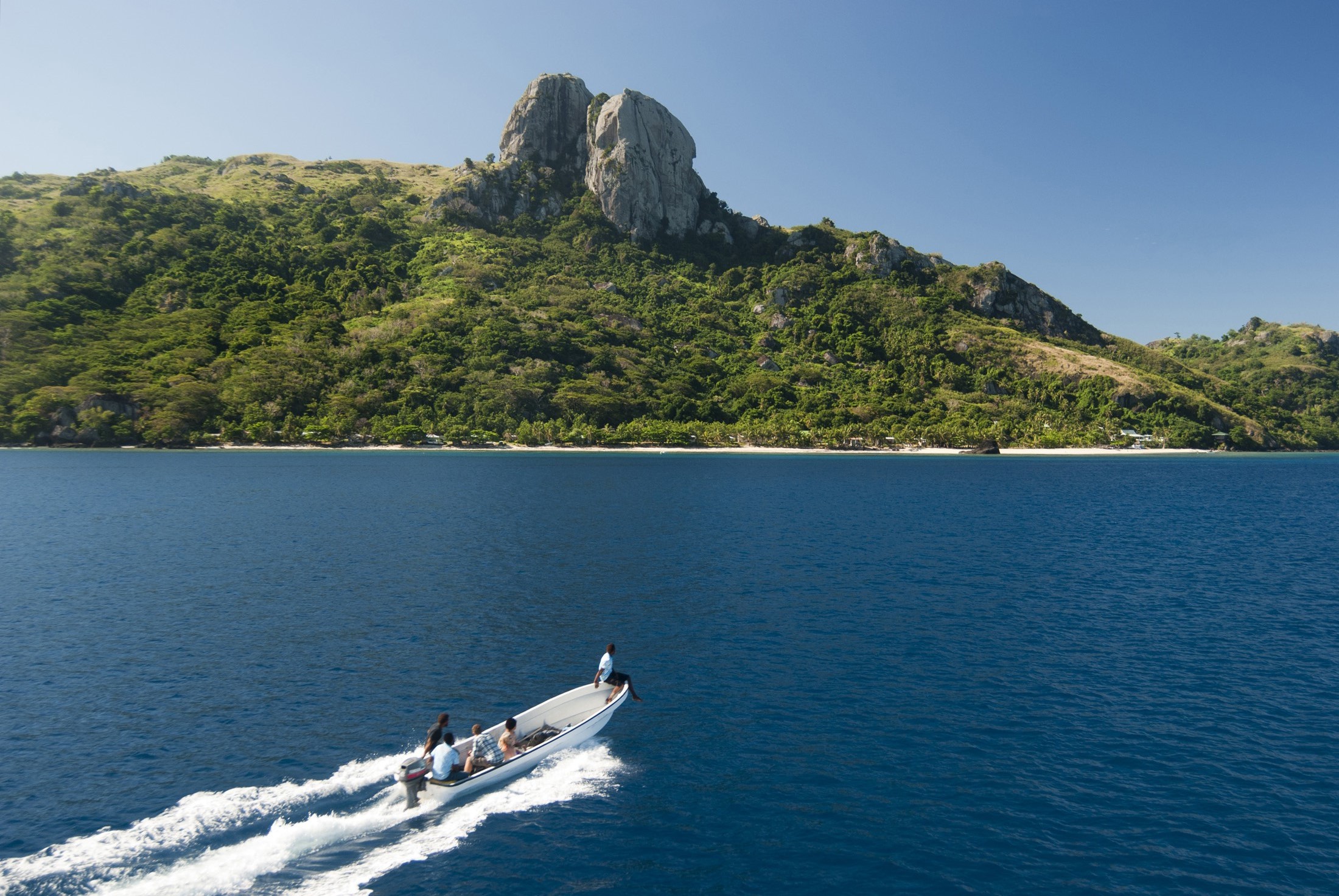 an image of Open motorboat with tourists approaching the coast of Waya island, Fiji, a popular tourist destination