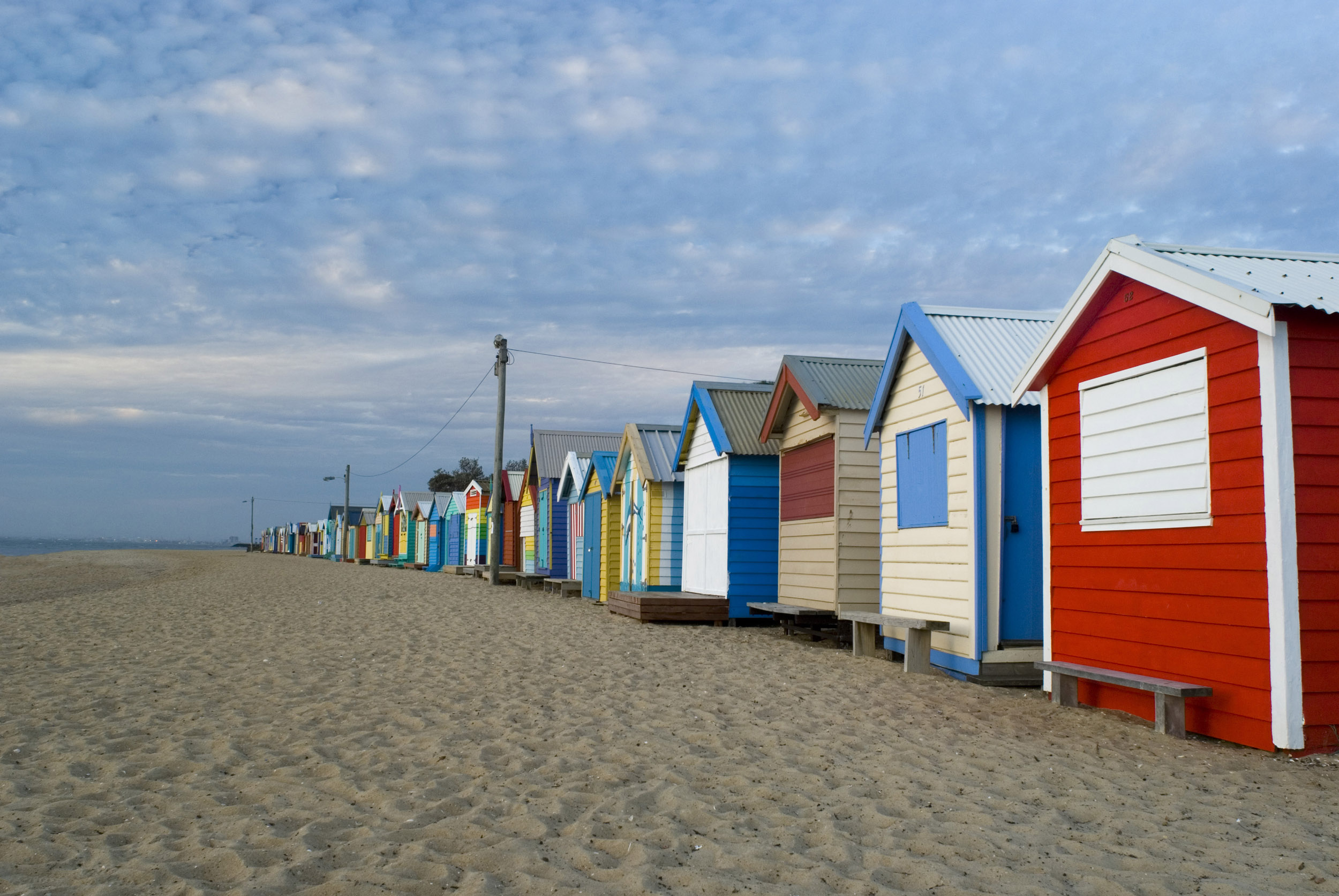 an image of A series of empty, rustic beach huts and shacks on a deserted beach in Brighton near Melbourne, Australia.