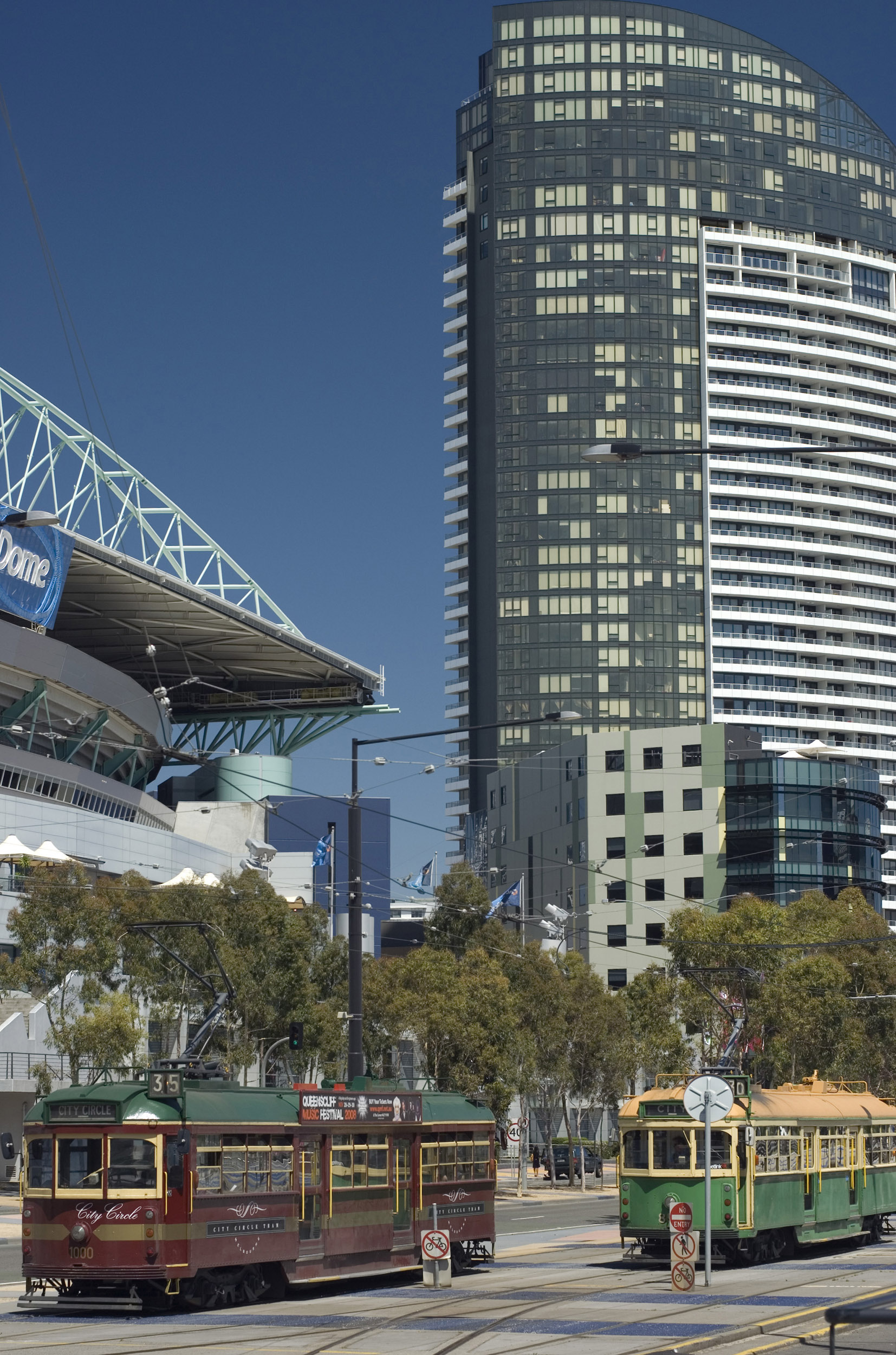 an image of The Telstra Dome in The Docklands, Melbourne, Australia with street trams and a skyscraper in a busy street scene