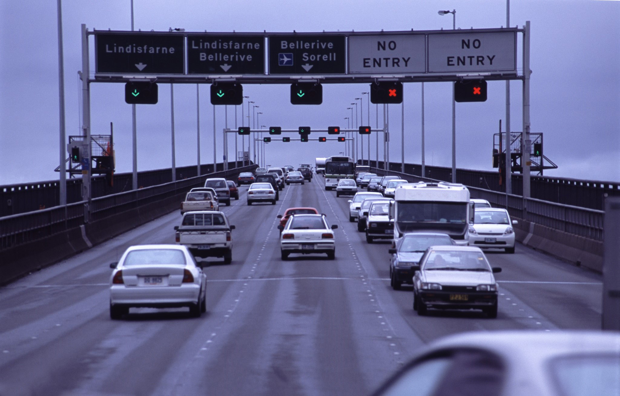 an image of Traffic on a highway driving below a set of overhead road signs on the on the Tasman Bridge, Hobart, Tasmania