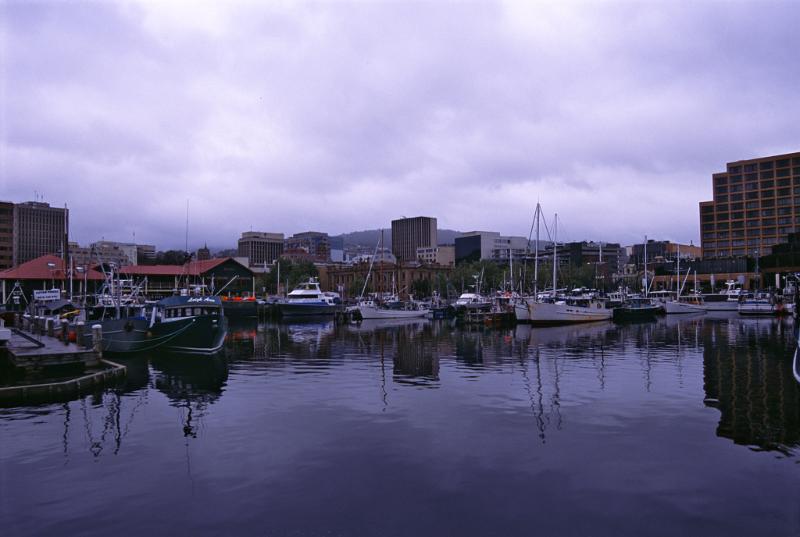 Hobart harbor, Tasmania on the Derwent River with a variety of ships and boats moored at the quays in sheltered water on a cloudy day