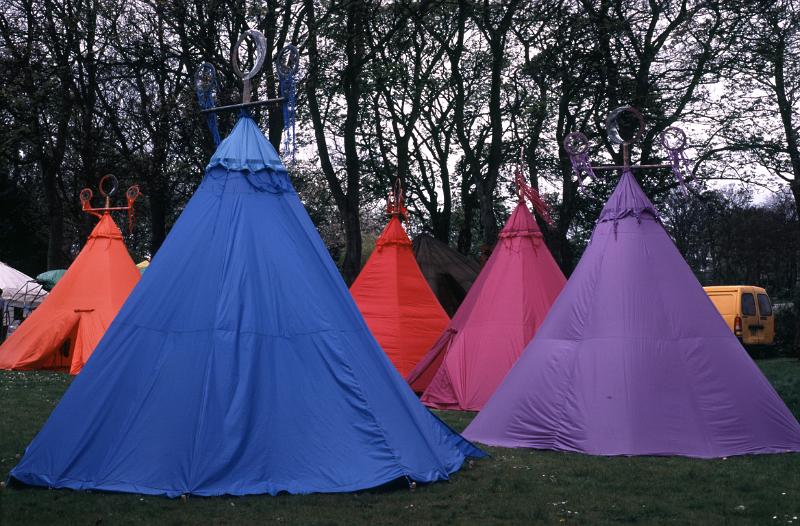 Group of colorful blue, orange and pink tents pitched on a wooded campsite conceptual of a vacation, travel and healthy lifestyle