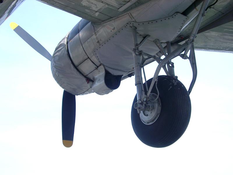 Retro plane with a view from underneath of the propeller and a single landing wheel as it flies overhead