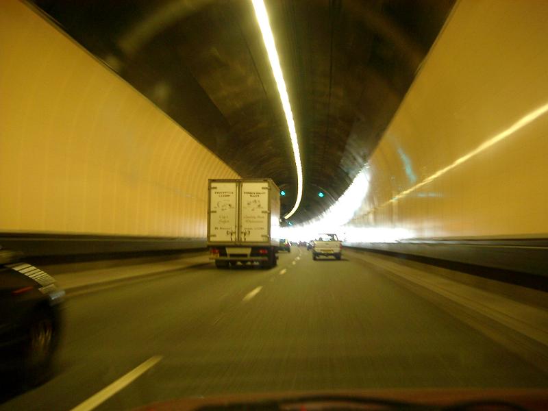 Interior of a road tunnel with traffic with cars and trucks passing around a curve in the road
