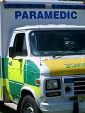 Close up detail of an ambulance showing the brightly colored signage on the door and large sign above the cab roof saying - Paramedic