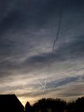 Vapor trails in a dark moody sky with heavy cloud cover at sunset criss-crossing the sky showing the routes of aircraft