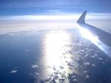 Wing tip of an airplane flying over cloud with a beam of bright sunlight in a travel, flying and vacation concept