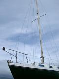 Yacht forecastle with a closeup view showing the bow and front mast with its rigging and stays against a cloudy sky