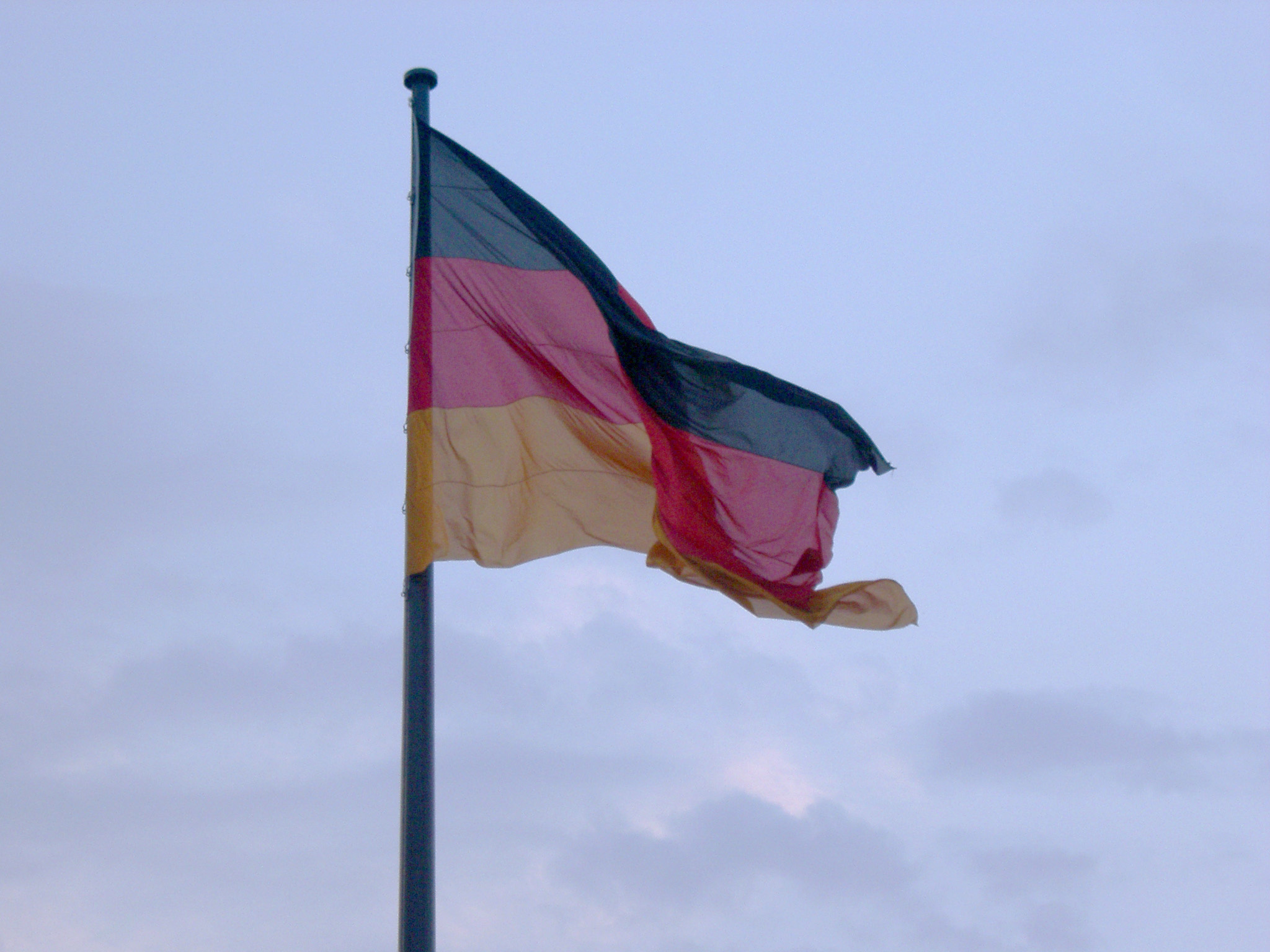 an image of Flag of Germany fluttering in the wind against a cloudy sky, symbol of German national pride and identity