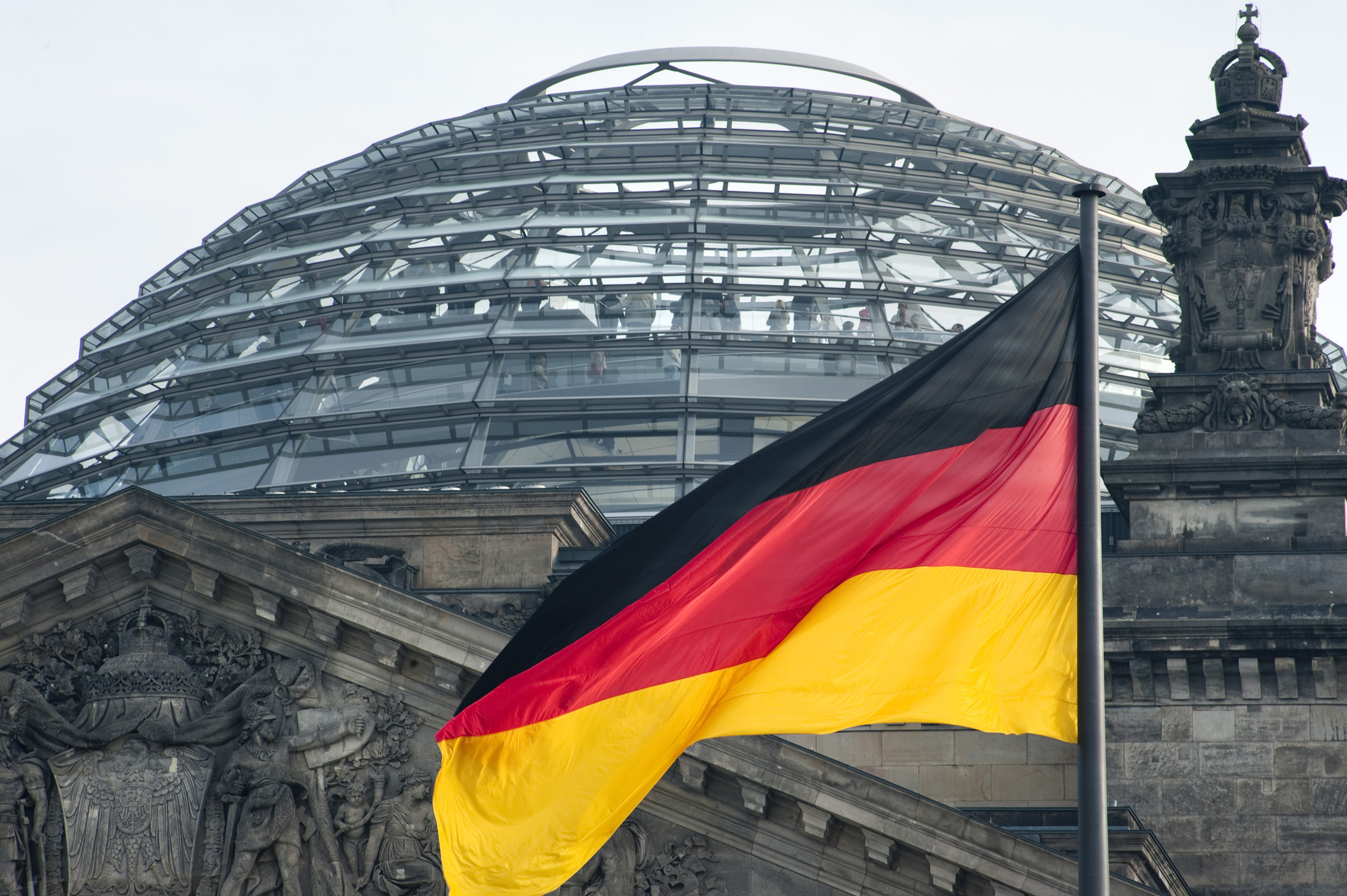 an image of red black and gold colors of the German national flag with the Reichstag german parliament building and dome to the rear