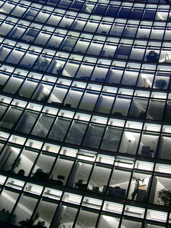 Rows of identical office windows on a modern office block viewed at a tilted low angle with reflections, architectural background