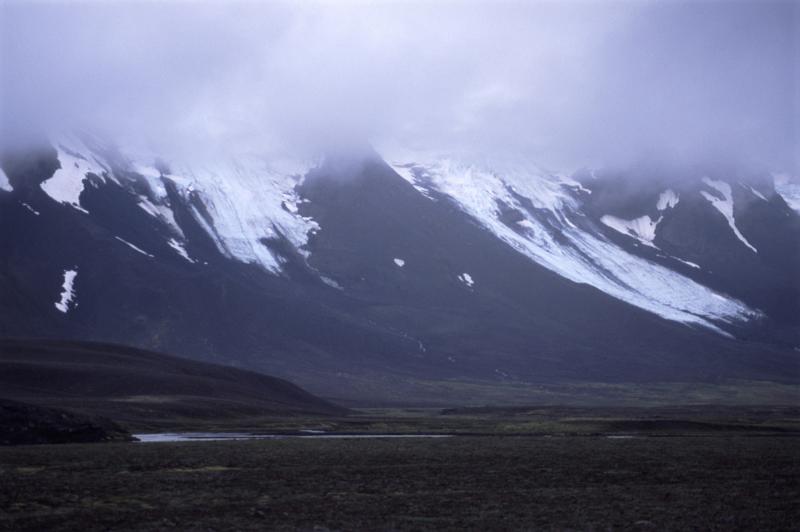 Icelandic landscape with glaciers descending from high volcanic peaks shrouded in cloud and mist