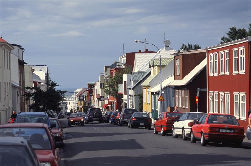 Street scene in Reykjavik, Iceland with traditional architecture and rows of parked cars on a sunny day