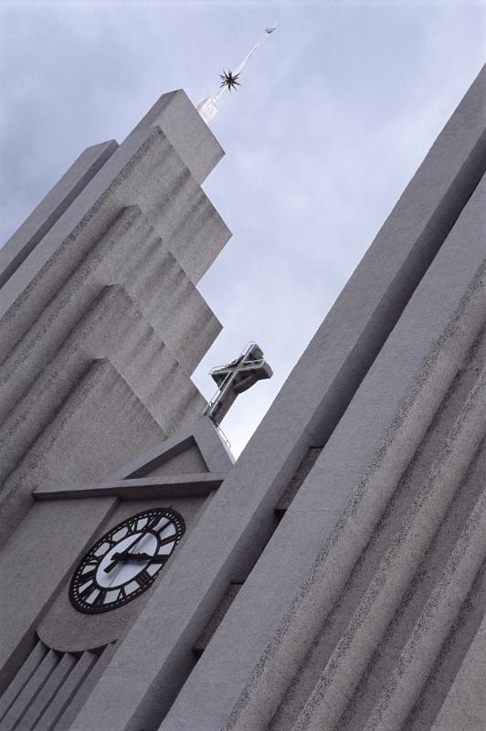 Close-up of the facade of the Lutheran Church of Akureyri, from Iceland, with a Christian cross mounted above the clock, concept of faith and time