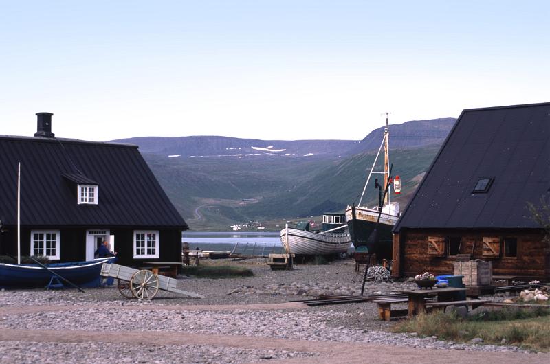 Iceland village on the edge of a bay or meltwater lake with fishing boats pulled ashore on the sand between the cottages