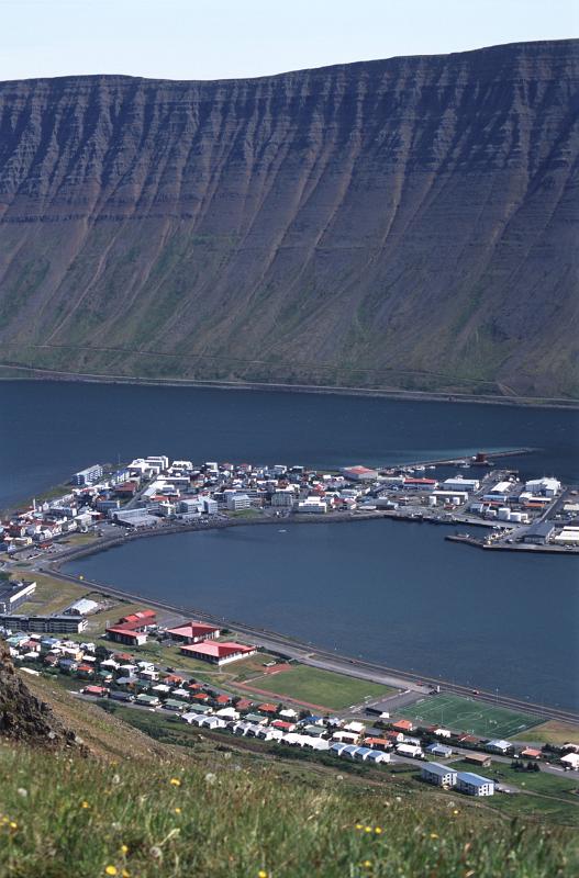 Scenic landscape aerial view of Isafjordur in Iceland, a remote fishing town in the fjords nesting under a volcanic mountain peak at the edge of a bay