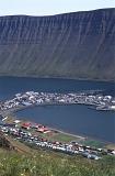 Scenic landscape aerial view of Isafjordur in Iceland, a remote fishing town in the fjords nesting under a volcanic mountain peak at the edge of a bay