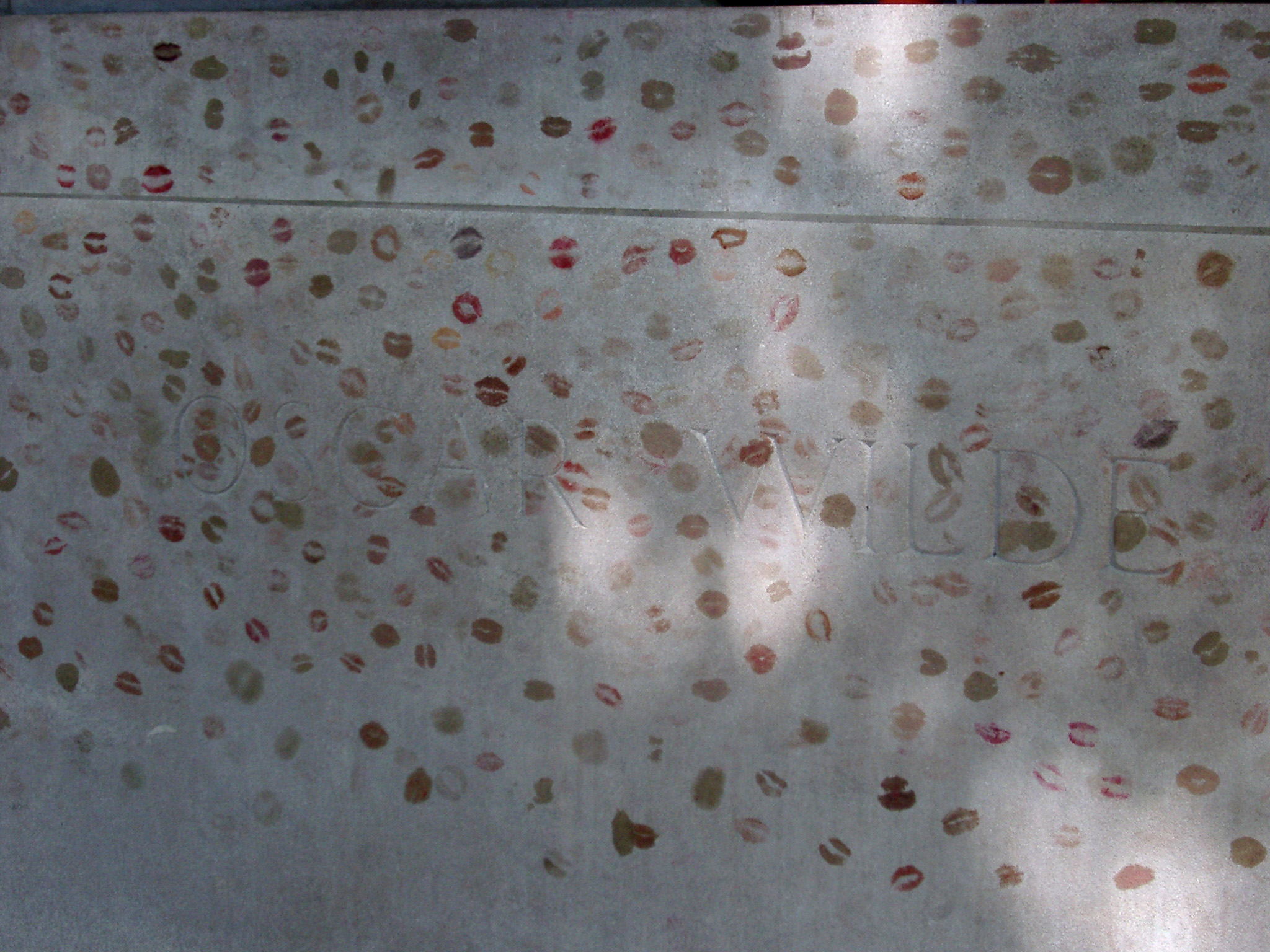an image of Close up Oscar Wilde Grave Filled with Various Kiss Marks