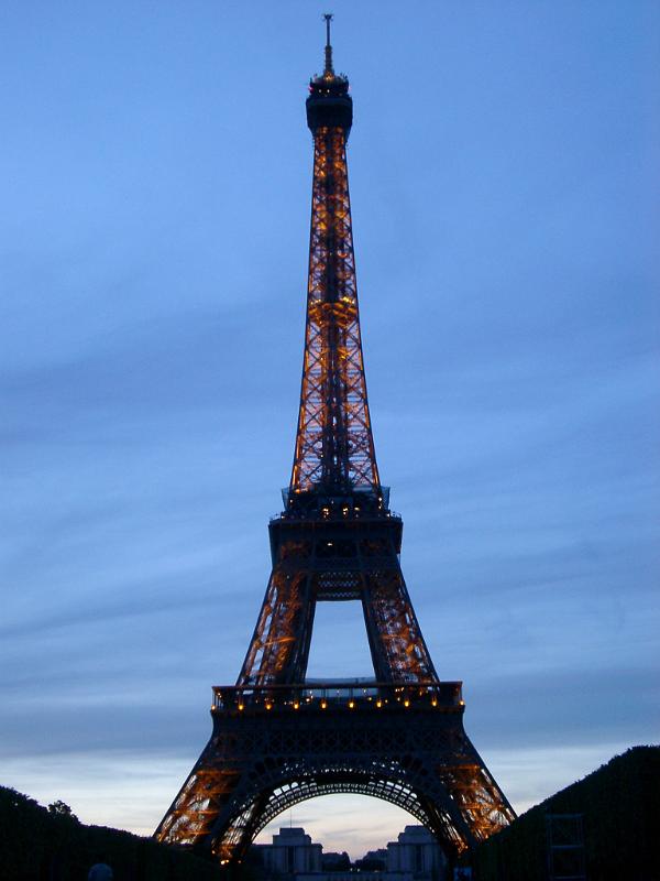 View of the iconic Eiffel Tower in Paris at dusk with the lights illuminated in a travel and vacation concept