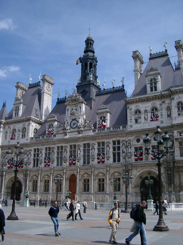 Exterior view of the ornate historical stone facade of the Paris City Hall or Hotel de Ville with pedestrians in the foreground
