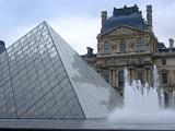 The glass pyramid at the Louvre, Paris with the ornamental fountains and external facade of the museum behind