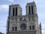 View of the historical front facade of the Notre Dame Cathedral in Paris, France against a blue sky