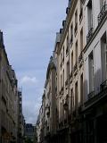 Paris, France, street view looking up at the historic facades of the buildings lining the road against a blue sky