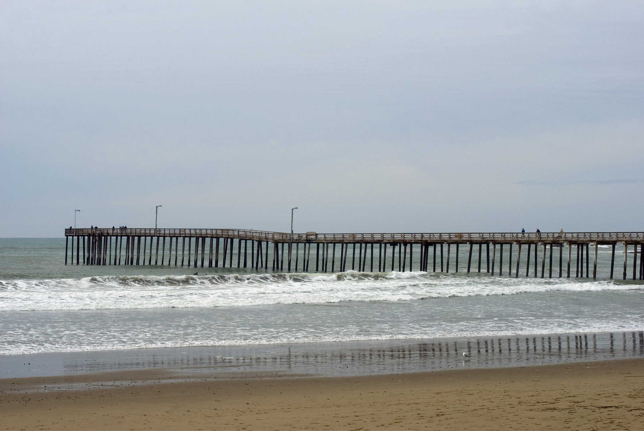 an image of Beautiful Beach Spot at Cayucos Pier in Extensive View. Isolated on Lighter Blue Gray Sky Background.