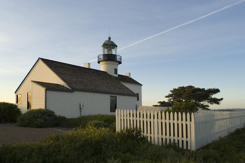Old Point Loma Lighthouse Surrounded by Green Plants. Isolated on Light Blue Sky Background.
