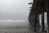 View Underneath the Wooden Columns at Cayucos Pier. Isolated on Light Gray Sky Background.