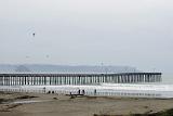 Tourists at Beautiful Cayucos Pier. Captured in Extensive View with Morro Rock Afar. Isolated on Foggy Sky Background.