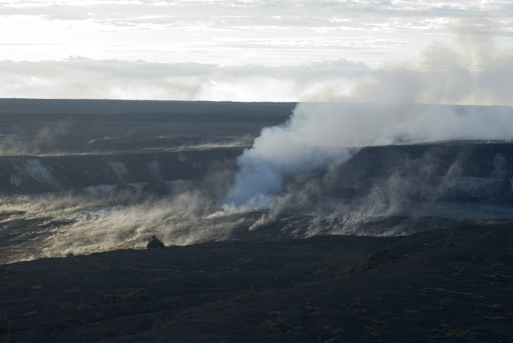 an image of Volcanoes National Park, Hawaii with a view of the Halemaumau crater, on the Kilauea caldera erupting in a cloud of hot vapor and steam